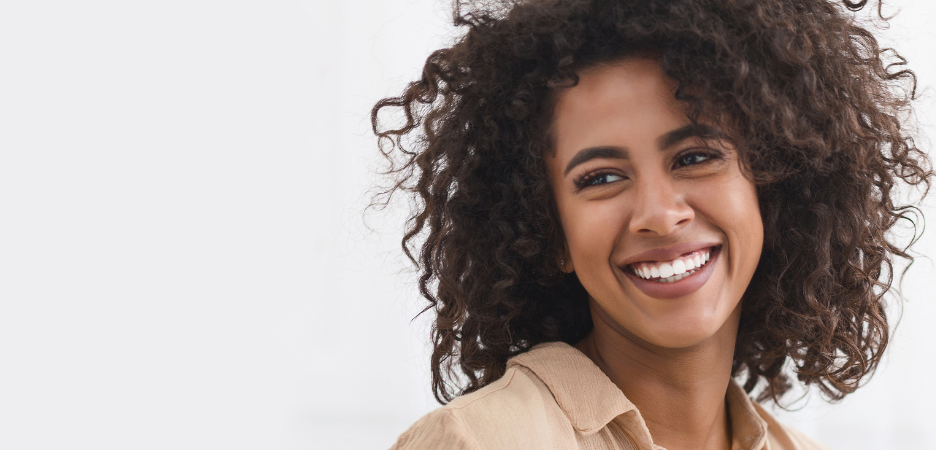 smiling black woman with curly brown hair and white teeth