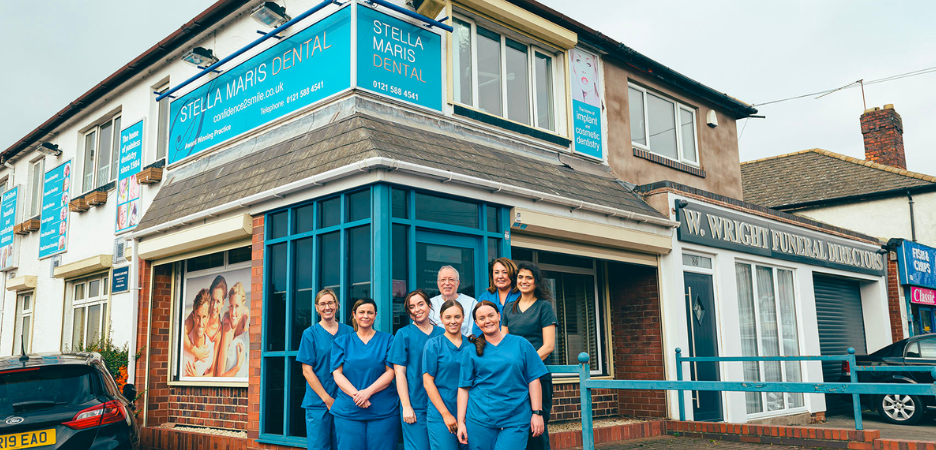 either members of staff from Stella Maris Dental standing outside their practice in uniform, smiling and happy to showcase their clinic