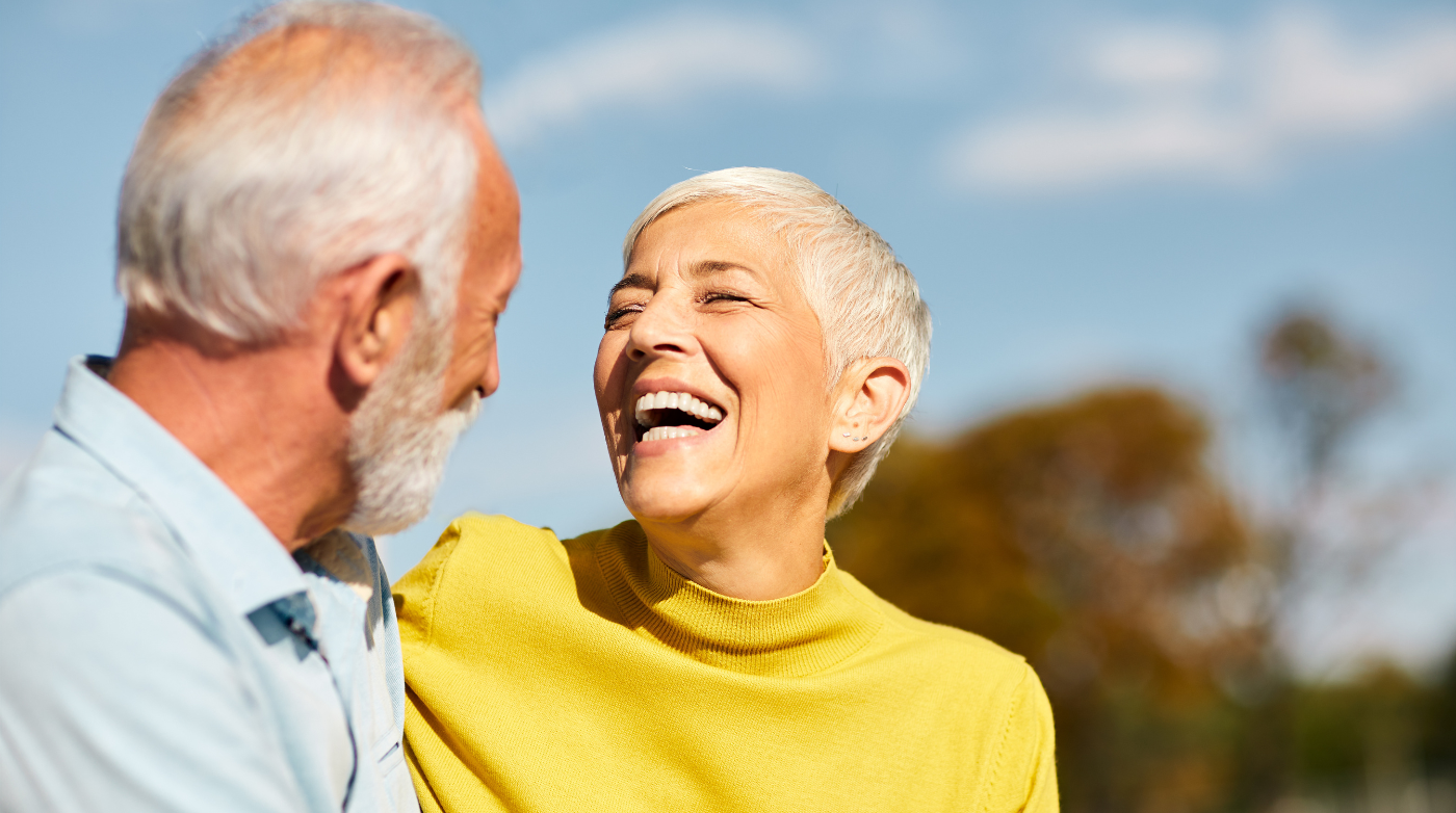 Older woman smiling with full set of teeth with husband