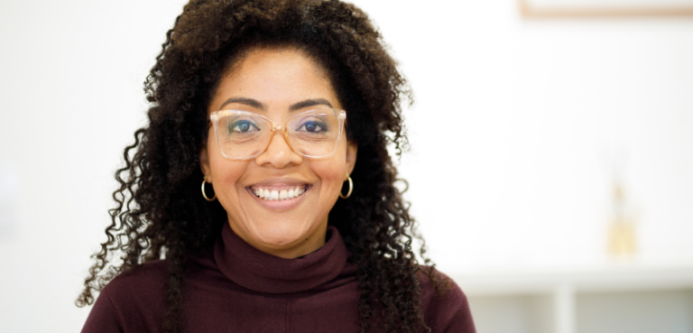 Black woman smiling at camera with big grin and glasses