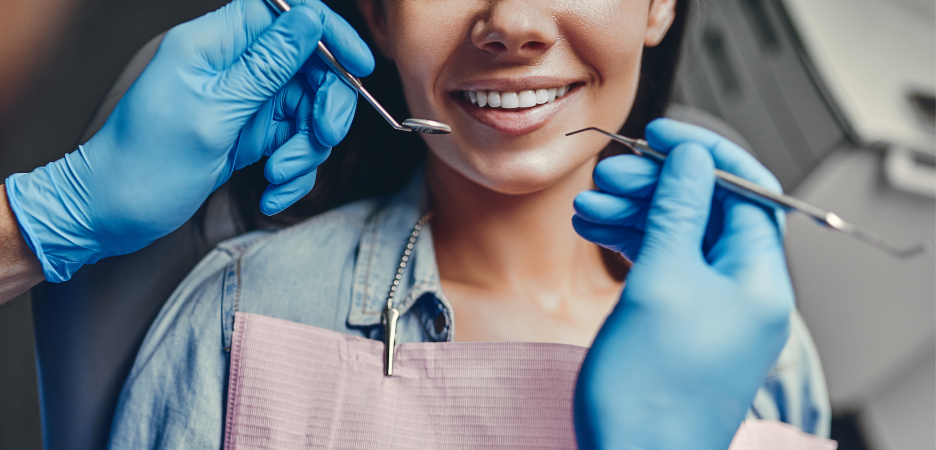 Close up of dentist with tools about to look inside a lady's mouth