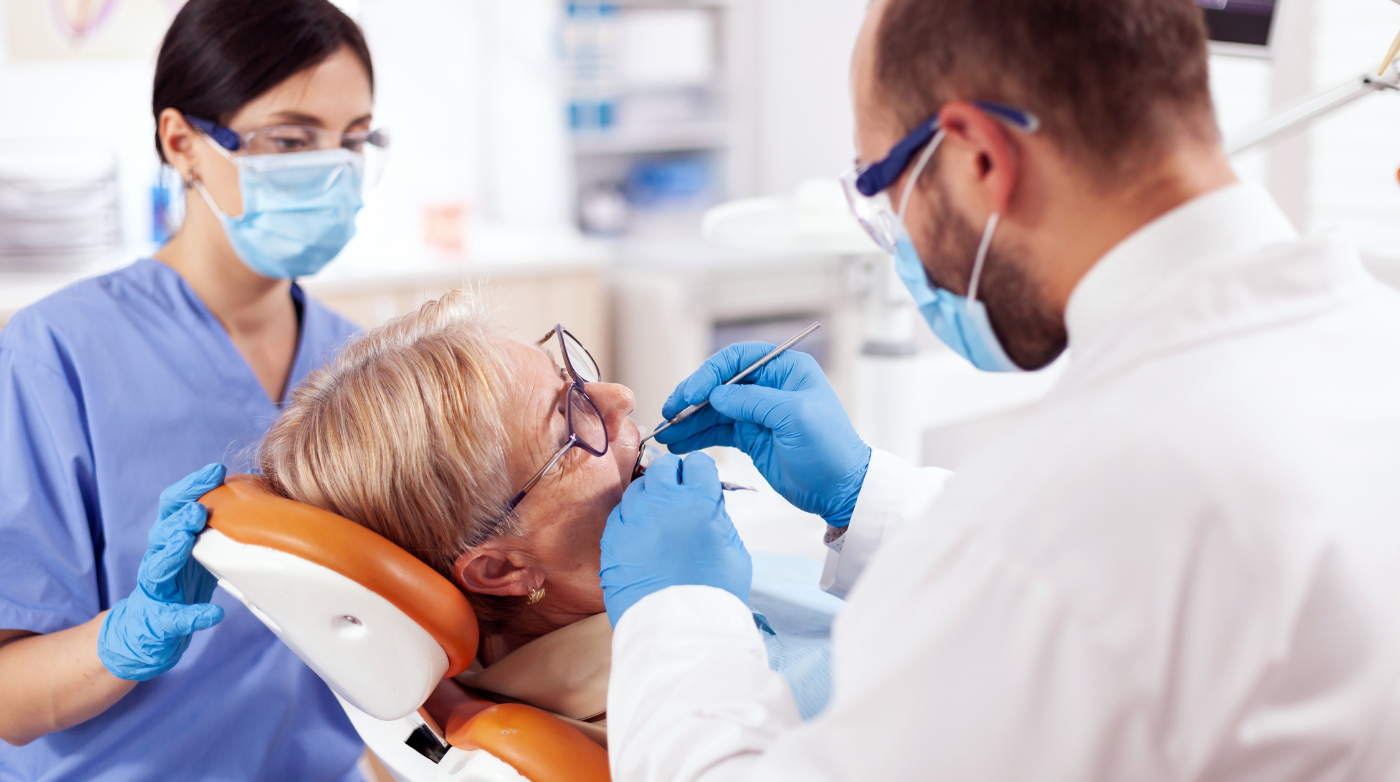 2 dentists providing emergency dental treatment to older woman in the dental chair